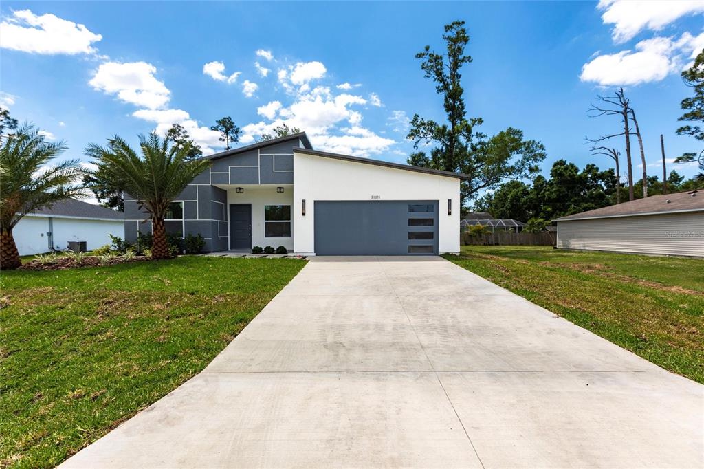A modern single-story house with a gray and white exterior and a concrete driveway — 12123 PLATANO DRIVE, PUNTA GORDA, FL