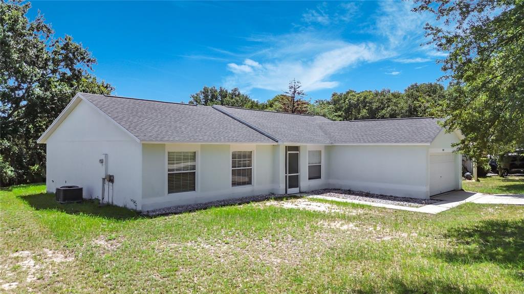 A single-story house with a light-colored exterior, a gray shingled roof, and a garage — 15405 MARGAUX DRIVE, CLERMONT, FL