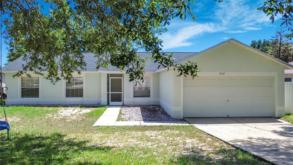 A single-story house with a light green exterior, a two-car garage, and a front walkway — 15405 MARGAUX DRIVE, CLERMONT, FL