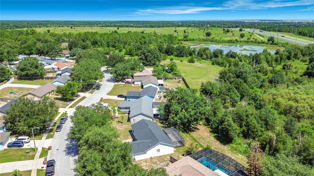 An aerial view shows a suburban neighborhood with houses, swimming pools, and surrounding green space — 15405 MARGAUX DRIVE, CLERMONT, FL