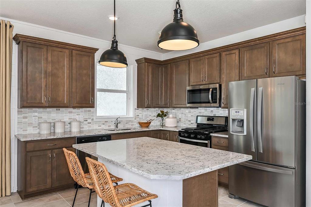 A kitchen with dark wood cabinets, granite countertops, stainless steel appliances, and a central island — 2623 HAMMOCK HARBOR AVENUE, ST CLOUD, FL