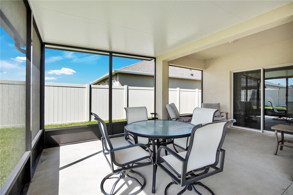 A backyard features a concrete patio with a screened-in enclosure and a covered roof — 3768 BOTANICAL WAY, SANFORD, FL