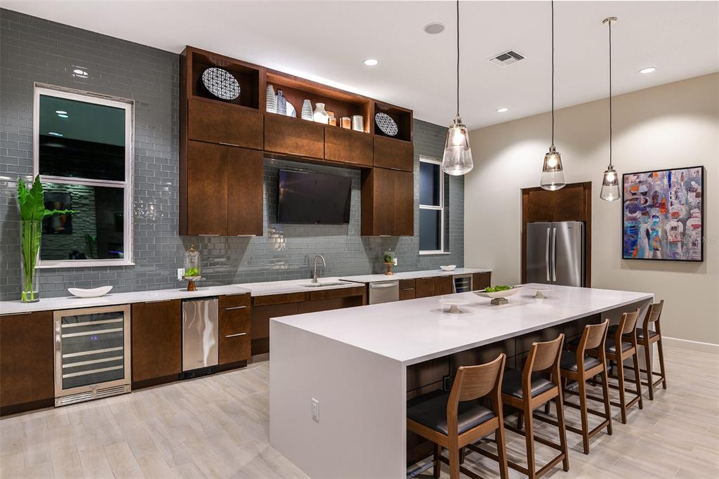 A modern kitchen features dark wood cabinetry, gray subway tile, a large white island, and barstools — 7545 LAUREATE BOULEVARD UNIT 7303, ORLANDO, FL
