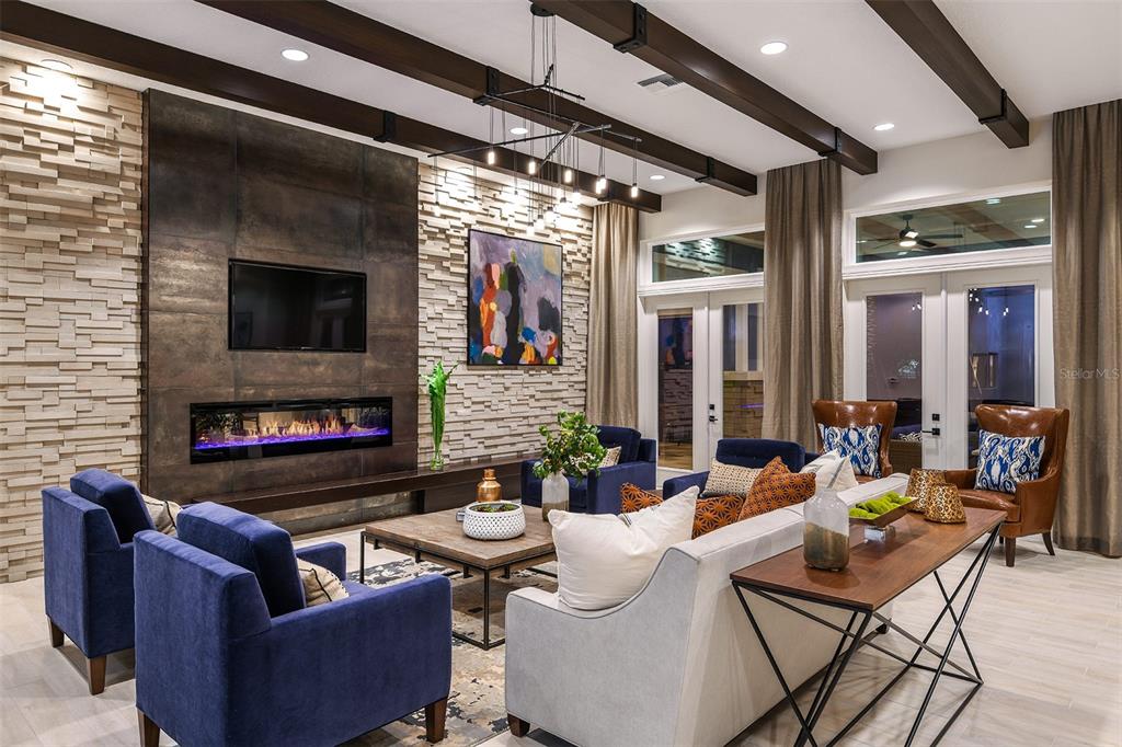 A living room features a stone accent wall, a fireplace, exposed ceiling beams, and blue furniture — 7545 LAUREATE BOULEVARD UNIT 7303, ORLANDO, FL