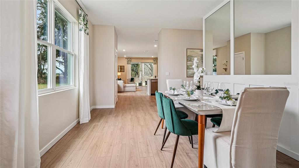 A dining room with wood-look flooring, a glass-topped table, and green upholstered chairs — 3999 NW 44TH CIRCLE, OCALA, FL