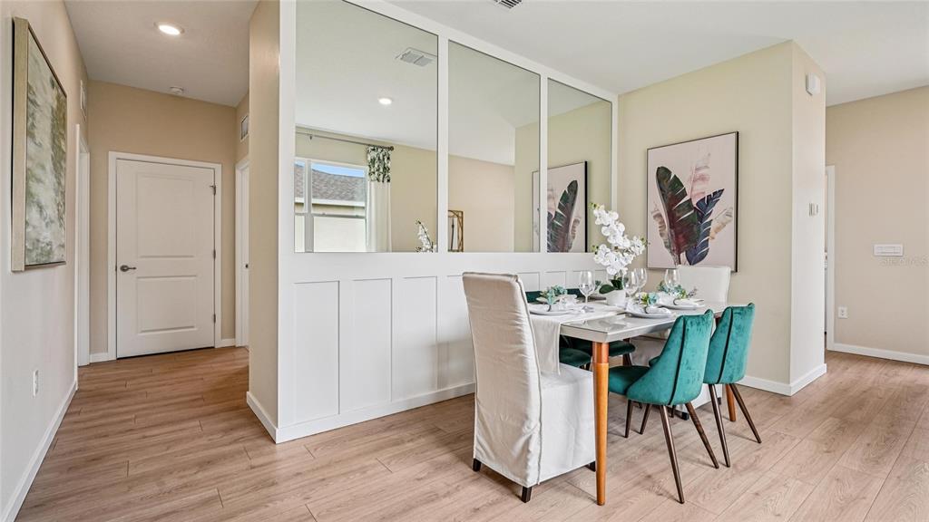 A dining area features a mirrored partition wall, wood-look flooring, and a table with chairs — 3999 NW 44TH CIRCLE, OCALA, FL