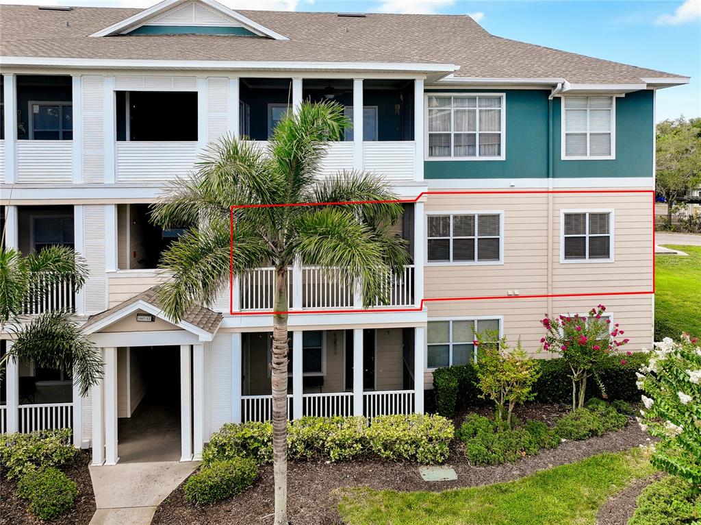 A three-story apartment building exterior features tan siding, white railings, and a palm tree — 4802 51ST STREET W UNIT 1410, BRADENTON, FL