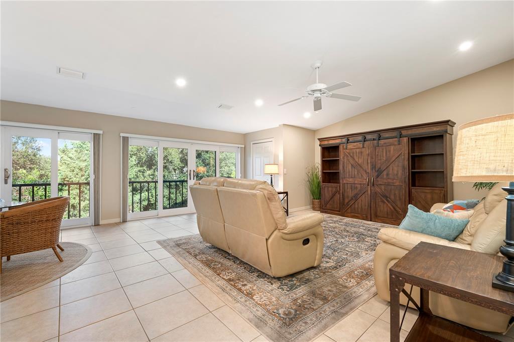 A living room features tile flooring, a large wooden entertainment center, and sliding glass doors — 2756 CLUBHOUSE DRIVE UNIT 202, SARASOTA, FL