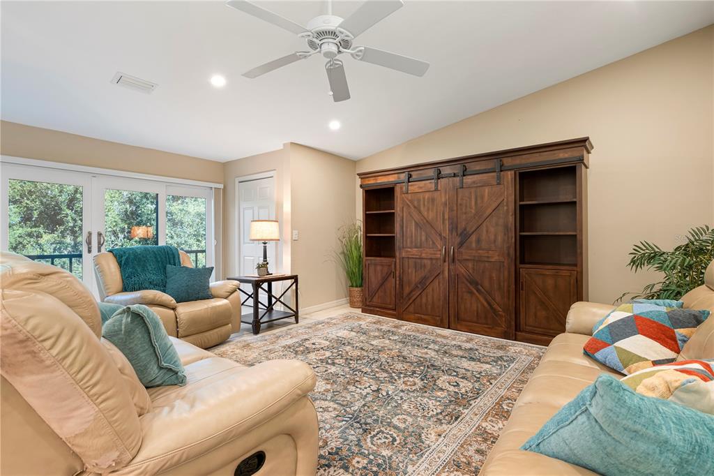 A living room features tan leather furniture, a large wooden media cabinet, and a patterned rug — 2756 CLUBHOUSE DRIVE UNIT 202, SARASOTA, FL