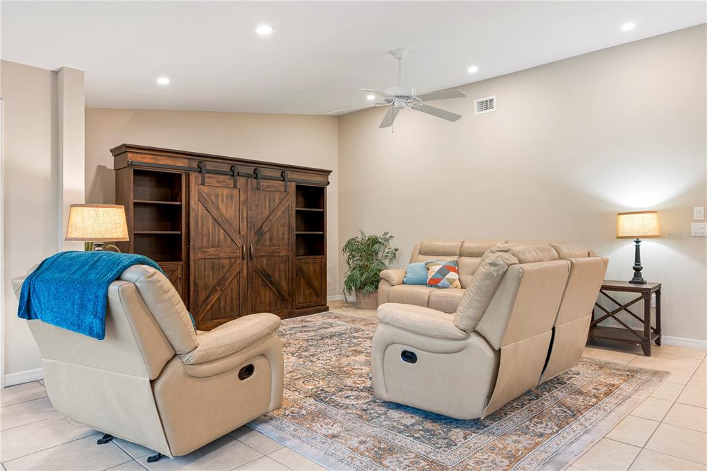 A living room features a large wooden entertainment center, two beige recliners, and a patterned rug — 2756 CLUBHOUSE DRIVE UNIT 202, SARASOTA, FL
