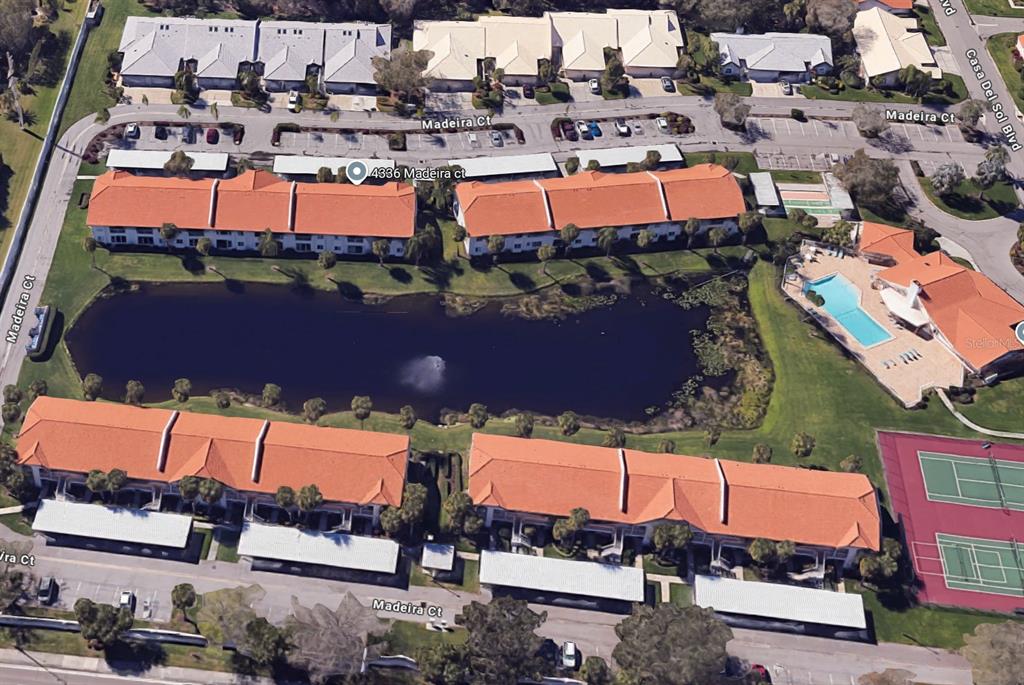 An aerial view shows a residential complex with four apartment buildings surrounding a central pond — 4268 MADEIRA COURT UNIT 3324, SARASOTA, FL