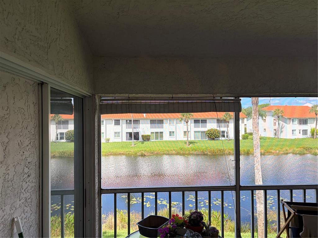 A screened-in balcony overlooks a pond and a multi-story apartment building — 4268 MADEIRA COURT UNIT 3324, SARASOTA, FL