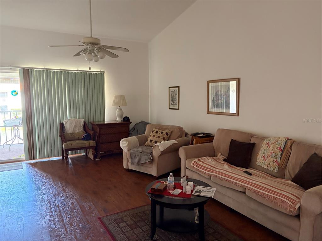A living room features wood flooring, a ceiling fan, beige furniture, and a sliding glass door — 4268 MADEIRA COURT UNIT 3324, SARASOTA, FL