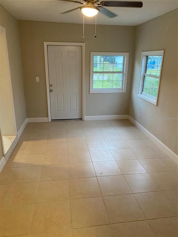A room with beige tile flooring, a white door, and two windows — 4321 LAKE LAWNE AVENUE, ORLANDO, FL