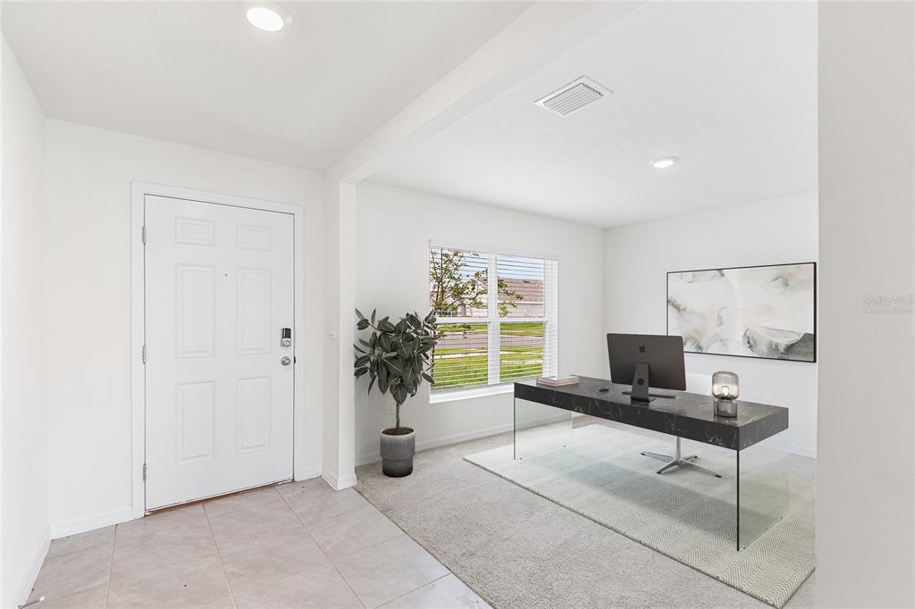 A home office features a glass-topped desk, a rug, and a window near the entryway — 5106 PLUMERIA DRIVE, WIMAUMA, FL