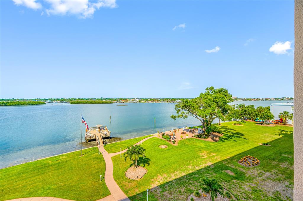 An elevated view of a grassy waterfront lawn with a wooden dock and a tree — 1847 SHORE DRIVE S UNIT 509, SOUTH PASADENA, FL