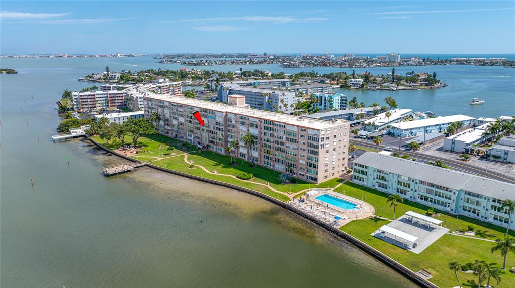 An aerial view shows a multi-story waterfront apartment building with a pool and green lawn — 1847 SHORE DRIVE S UNIT 509, SOUTH PASADENA, FL