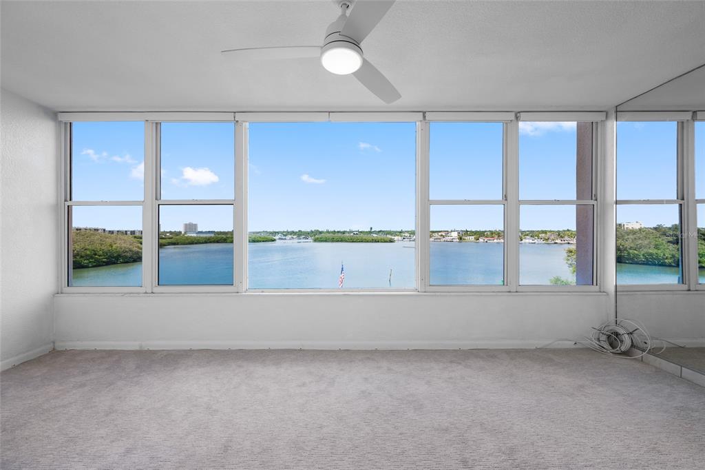 An empty room with beige carpet, a ceiling fan, and large windows overlooking the water — 1847 SHORE DRIVE S UNIT 509, SOUTH PASADENA, FL