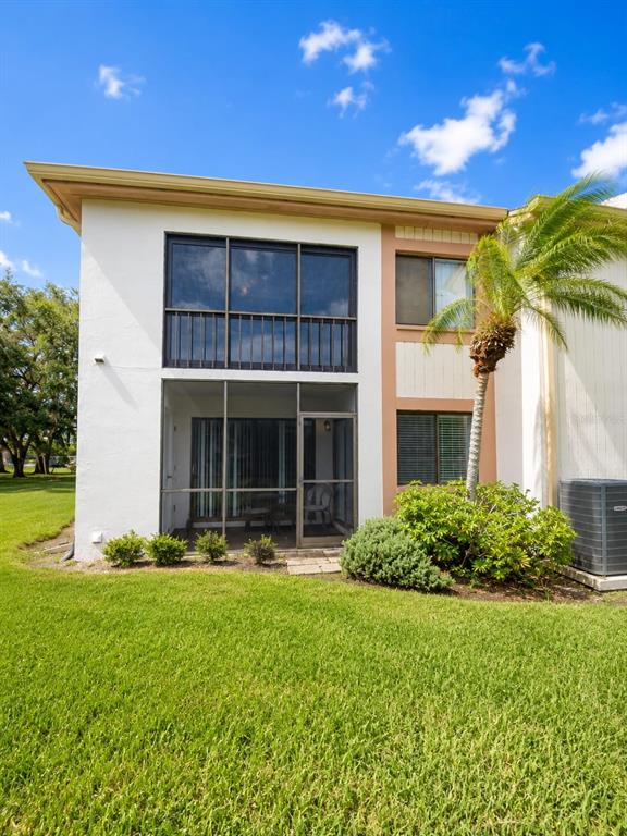 The exterior of a two-story residential building features a screened-in porch and a palm tree — 115 LAKEVIEW PLACE UNIT 115, OLDSMAR, FL