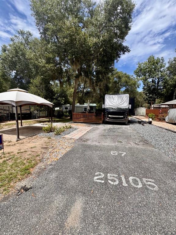 A paved campsite features a large gazebo, a parked RV, and a wooden deck — 25105 NE 143RD STREET, SALT SPRINGS, FL