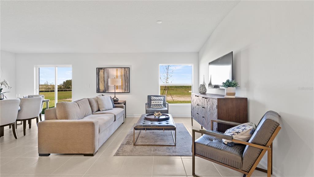 A living room features a beige sofa, a leather ottoman, and a view of fields — 1940 PINE MEADOWS GOLFCOURSE ROAD, EUSTIS, FL