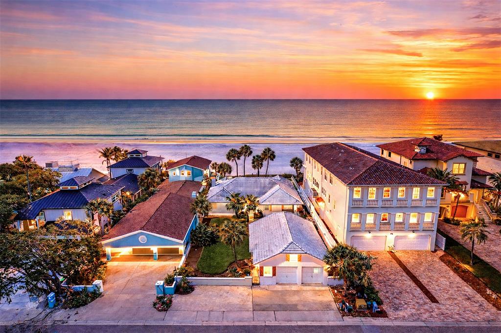 A grassy lawn with palm trees leads to a sandy beach at sunset — 18206 SUNSET BOULEVARD, REDINGTON SHORES, FL