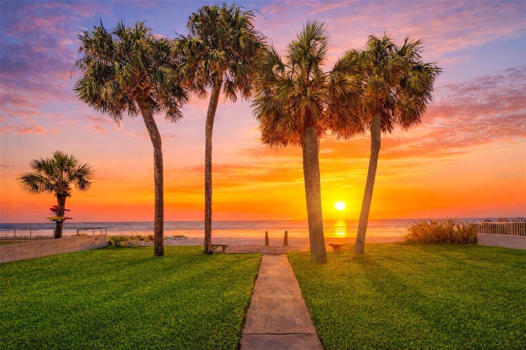 A white house with a two-car garage and palm trees at sunset — 18206 SUNSET BOULEVARD, REDINGTON SHORES, FL