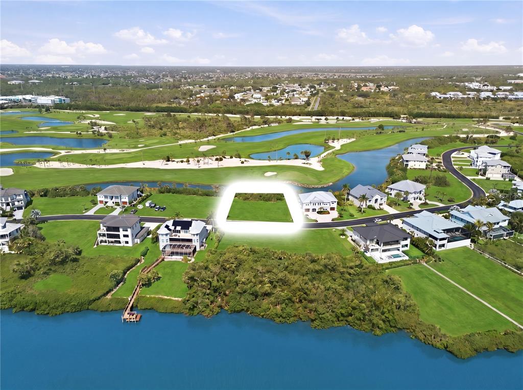 An aerial view shows a vacant residential lot highlighted in a neighborhood near water — 10000 EAGLE PRESERVE DRIVE, ENGLEWOOD, FL