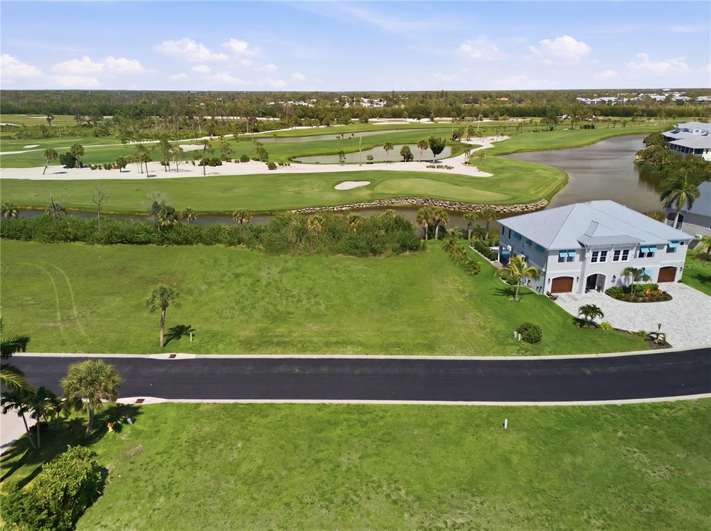 An aerial view shows a vacant residential lot next to a house overlooking a golf course — 10000 EAGLE PRESERVE DRIVE, ENGLEWOOD, FL