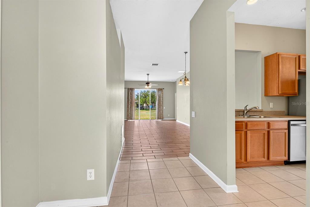 A view from a tiled kitchen area looking toward a living room with sliding doors — 9784 50TH STREET CIRCLE E, PARRISH, FL