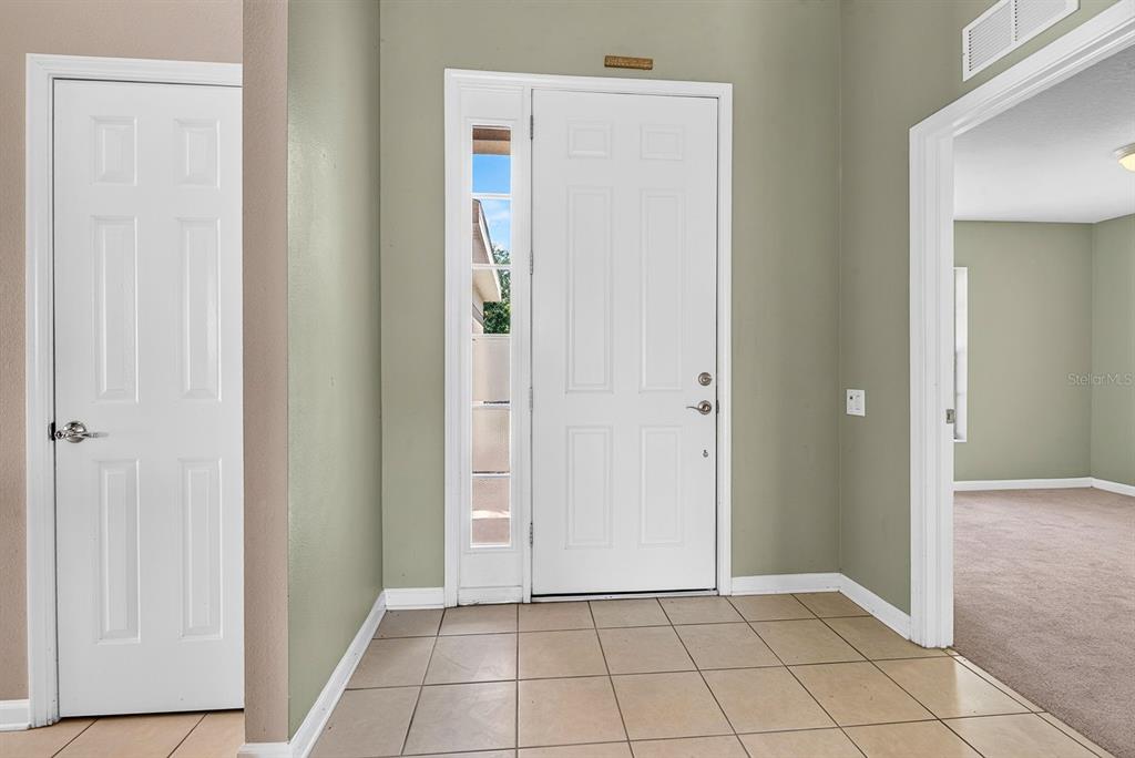 An entryway features a white front door with a sidelight, tile flooring, and light-green walls — 9784 50TH STREET CIRCLE E, PARRISH, FL