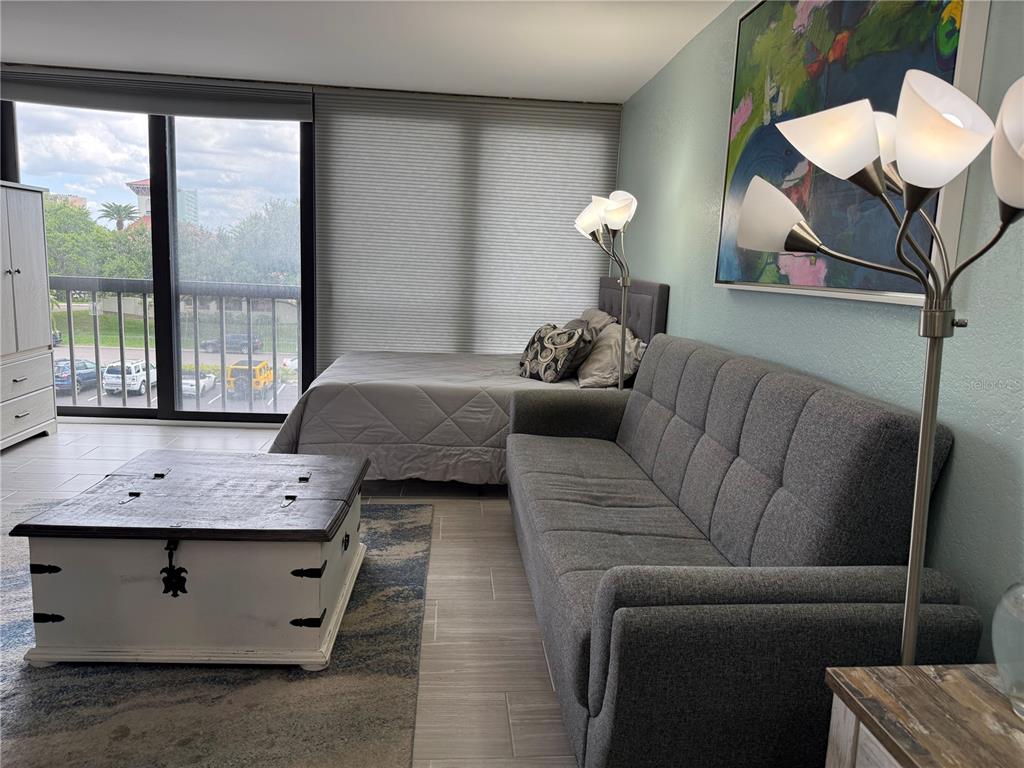 A studio apartment features a bed, a gray sofa, a coffee table, and a balcony — 255 DOLPHIN POINT UNIT 305, CLEARWATER BEACH, FL