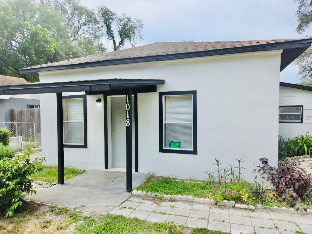 A white, single-story house with a black-trimmed porch, windows, and roofline — 1018 E HOLLAND AVENUE, TAMPA, FL