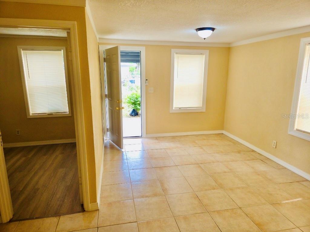 A room with beige walls, tile flooring, and an open door leading to the outdoors — 1018 E HOLLAND AVENUE, TAMPA, FL