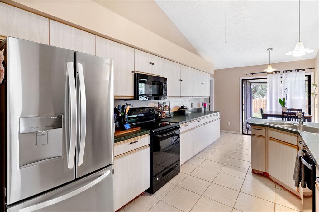 A kitchen with light wood cabinets, black appliances, a stainless steel refrigerator, and tile flooring — 1921 SW GRANELLO TERRACE, PORT ST LUCIE, FL
