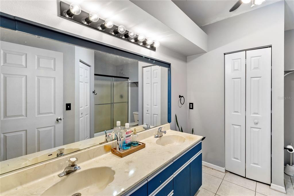A bathroom features a double-sink vanity with a large mirror and blue cabinets — 1921 SW GRANELLO TERRACE, PORT ST LUCIE, FL