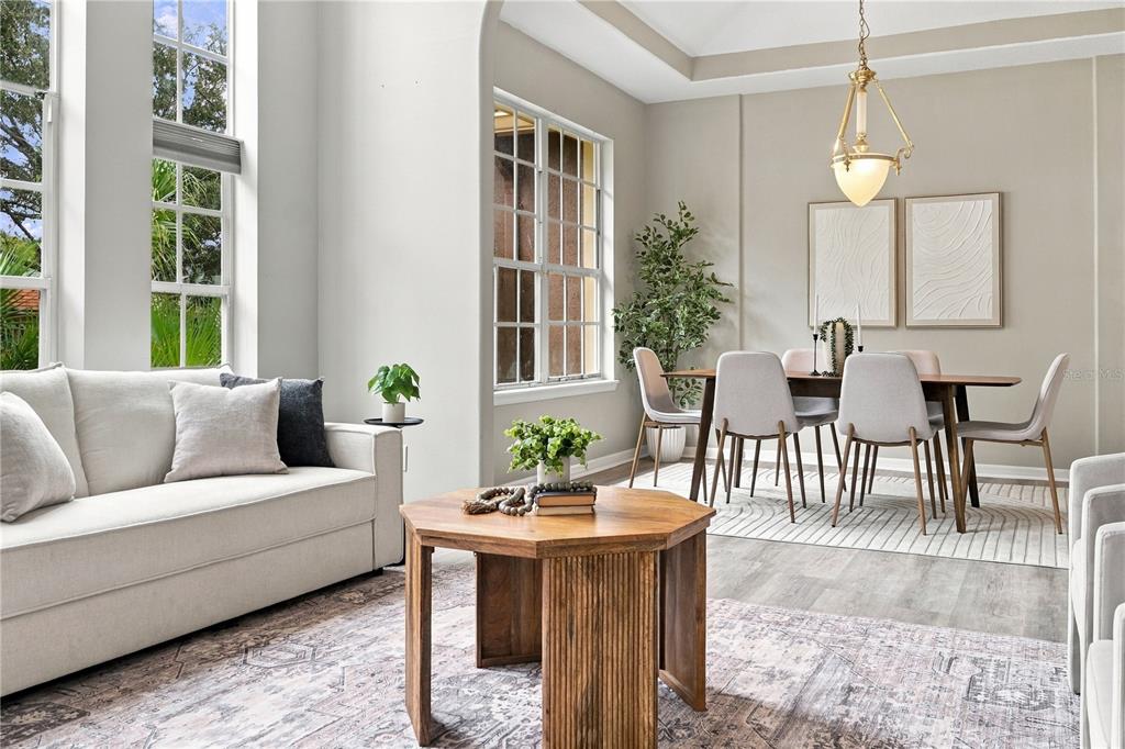 A living room with a beige sofa and wooden coffee table opens into a dining area — 7628 MILANO DRIVE, ORLANDO, FL