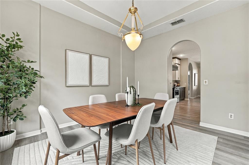 A dining room features a wooden table, six chairs, a chandelier, and an arched doorway — 7628 MILANO DRIVE, ORLANDO, FL