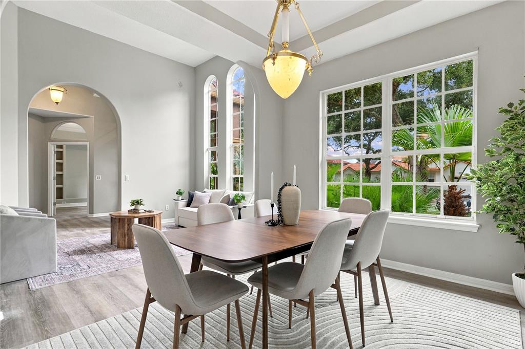 A dining room features a wooden table, light gray chairs, and tall arched windows — 7628 MILANO DRIVE, ORLANDO, FL