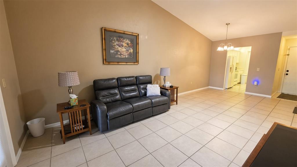 A living room features a dark leather sofa, tile flooring, and a vaulted ceiling — 95 E HARTFORD STREET Bldg 10, 8A, HERNANDO, FL