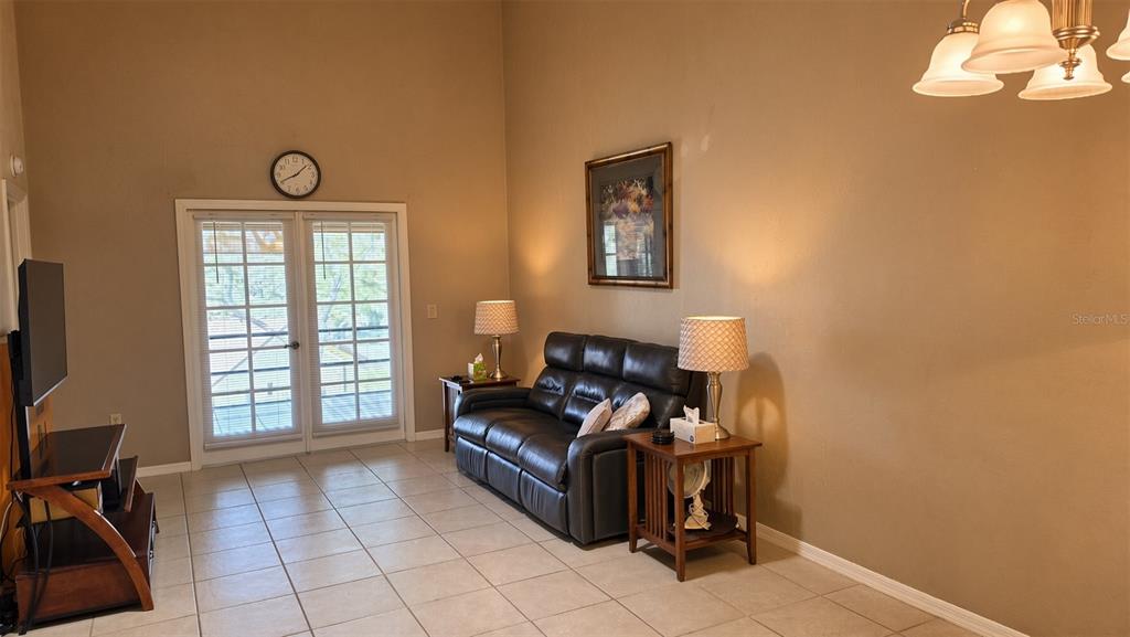 A living room features a dark leather sofa, tile flooring, and glass French doors — 95 E HARTFORD STREET Bldg 10, 8A, HERNANDO, FL