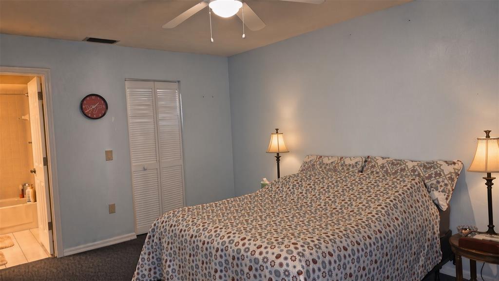 A bedroom with light blue walls, a patterned bedspread, two lamps, and an attached bathroom — 95 E HARTFORD STREET Bldg 10, 8A, HERNANDO, FL