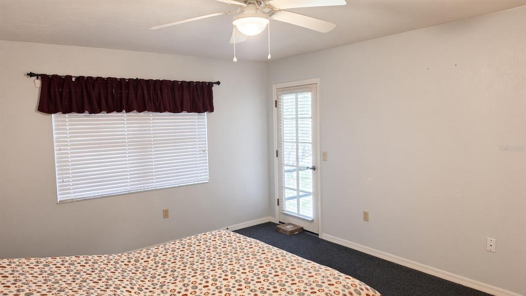 A bedroom features a ceiling fan, a window with a valance, and a glass-paneled door — 95 E HARTFORD STREET Bldg 10, 8A, HERNANDO, FL