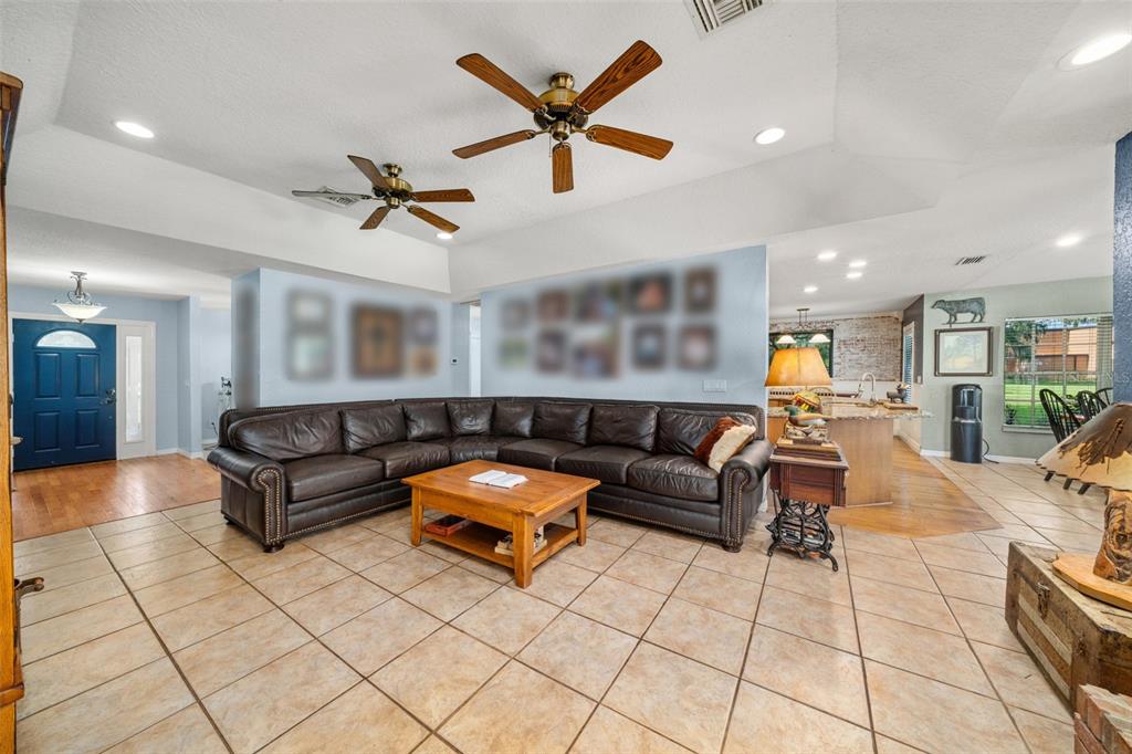 A living room features tile flooring, a brick fireplace, a large sectional, and two ceiling fans — 510 EDGEWOOD DRIVE, FORT MEADE, FL