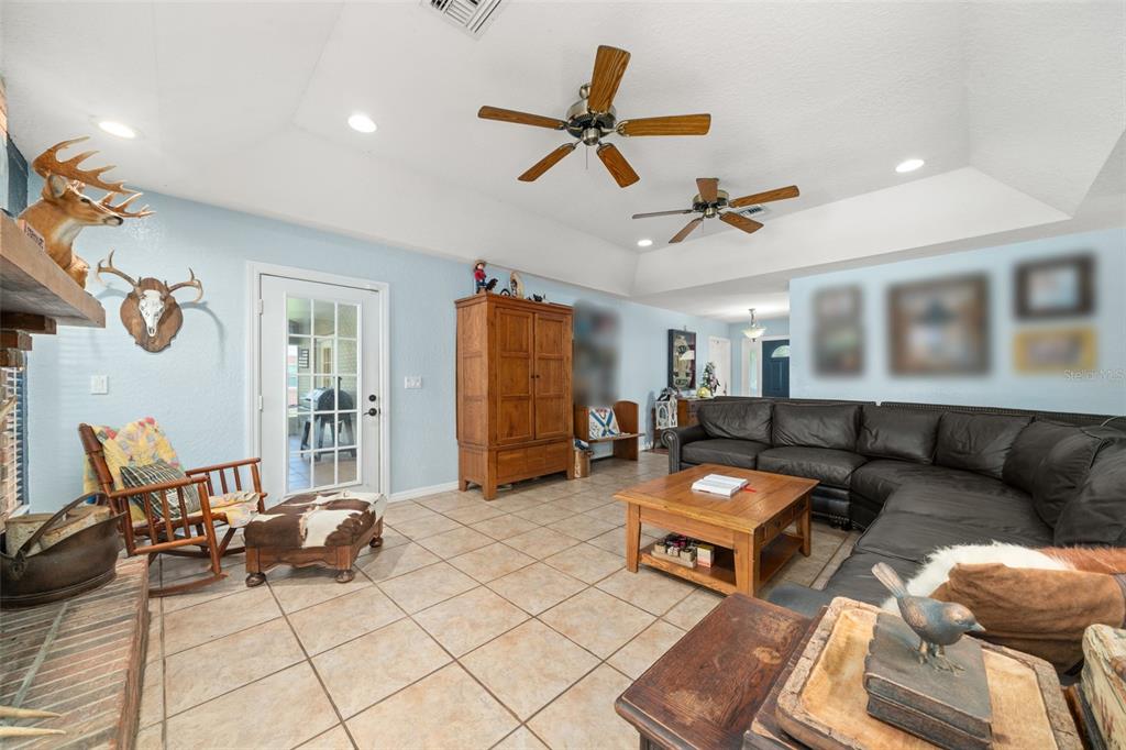 A living room features a brick fireplace, two ceiling fans, and dark leather sectional sofas — 510 EDGEWOOD DRIVE, FORT MEADE, FL