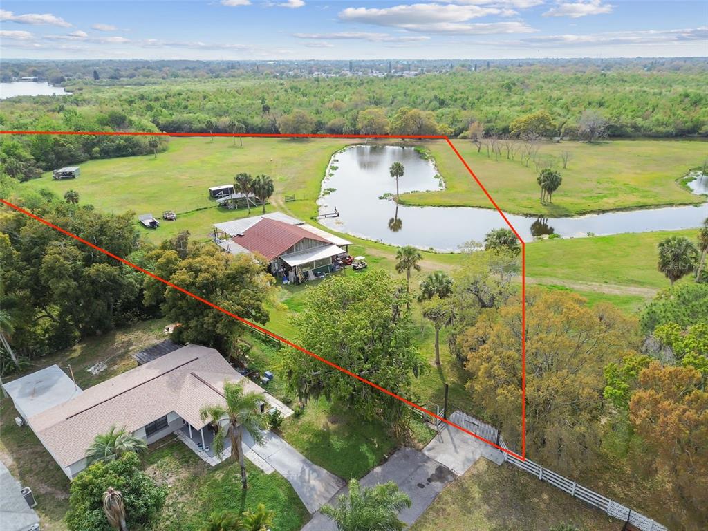 An aerial view shows a house, a large barn, and a pond on a grassy lot — KIBLER LN, HOLIDAY, FL