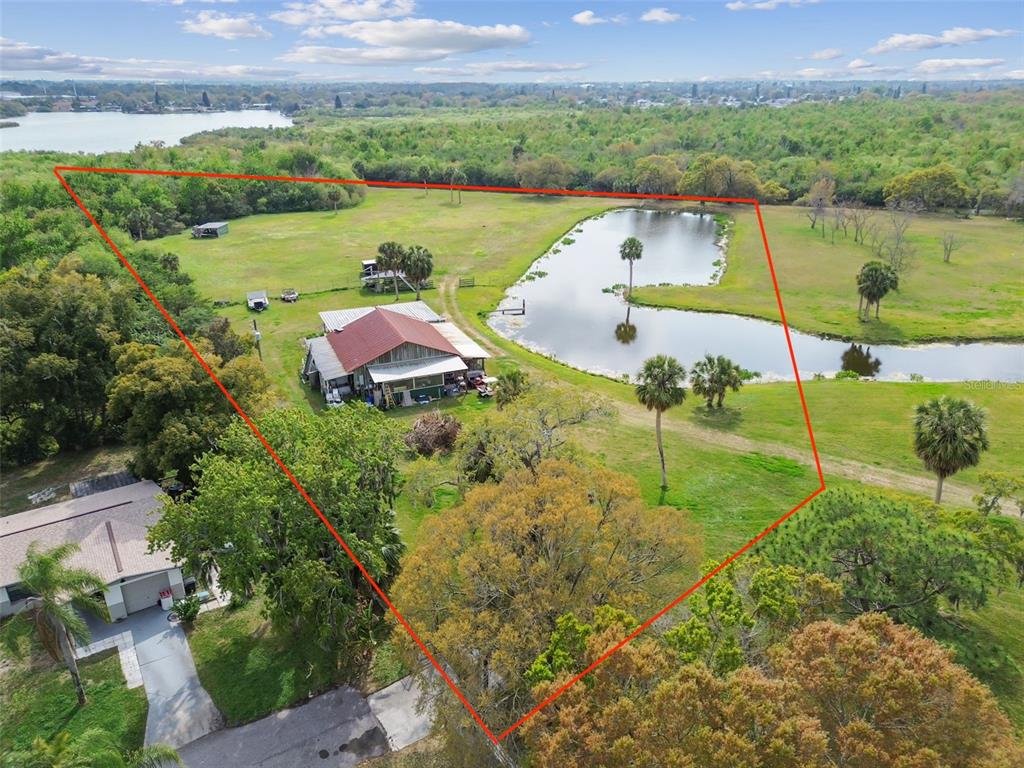 An aerial view shows a rural property with a house, a pond, and surrounding trees — KIBLER LN, HOLIDAY, FL