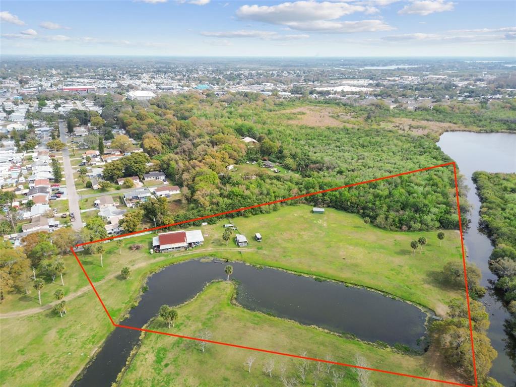 Aerial view of a rural property featuring a pond, a barn, and surrounding wooded areas — KIBLER LN, HOLIDAY, FL