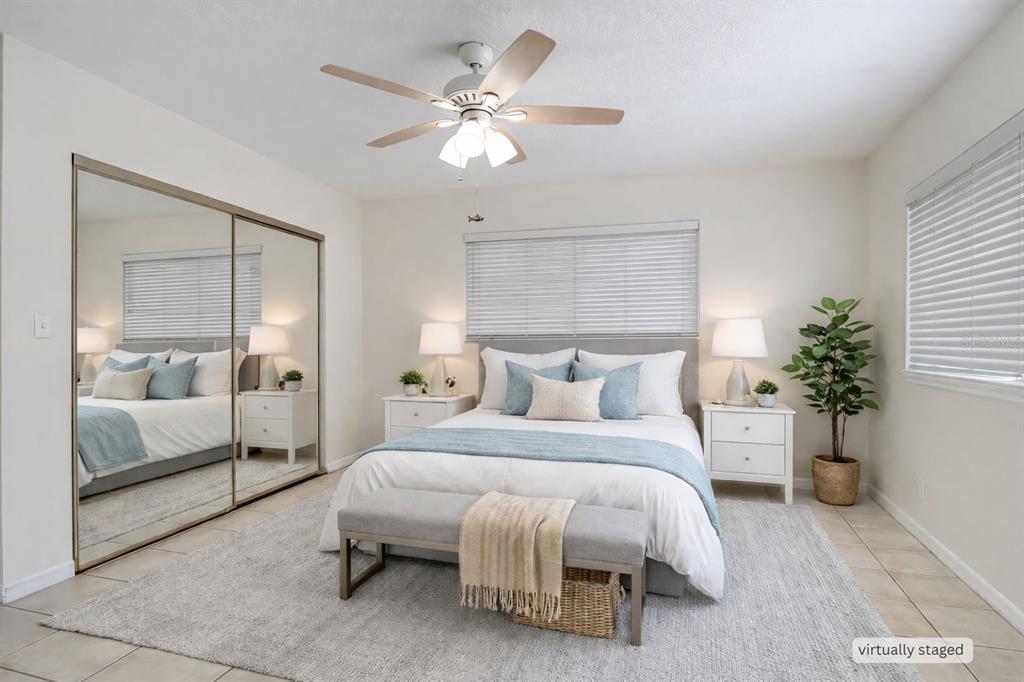 A bedroom with a queen bed, mirrored closet doors, a ceiling fan, and light-colored flooring — 4621 JOHN MOORE ROAD, BRANDON, FL