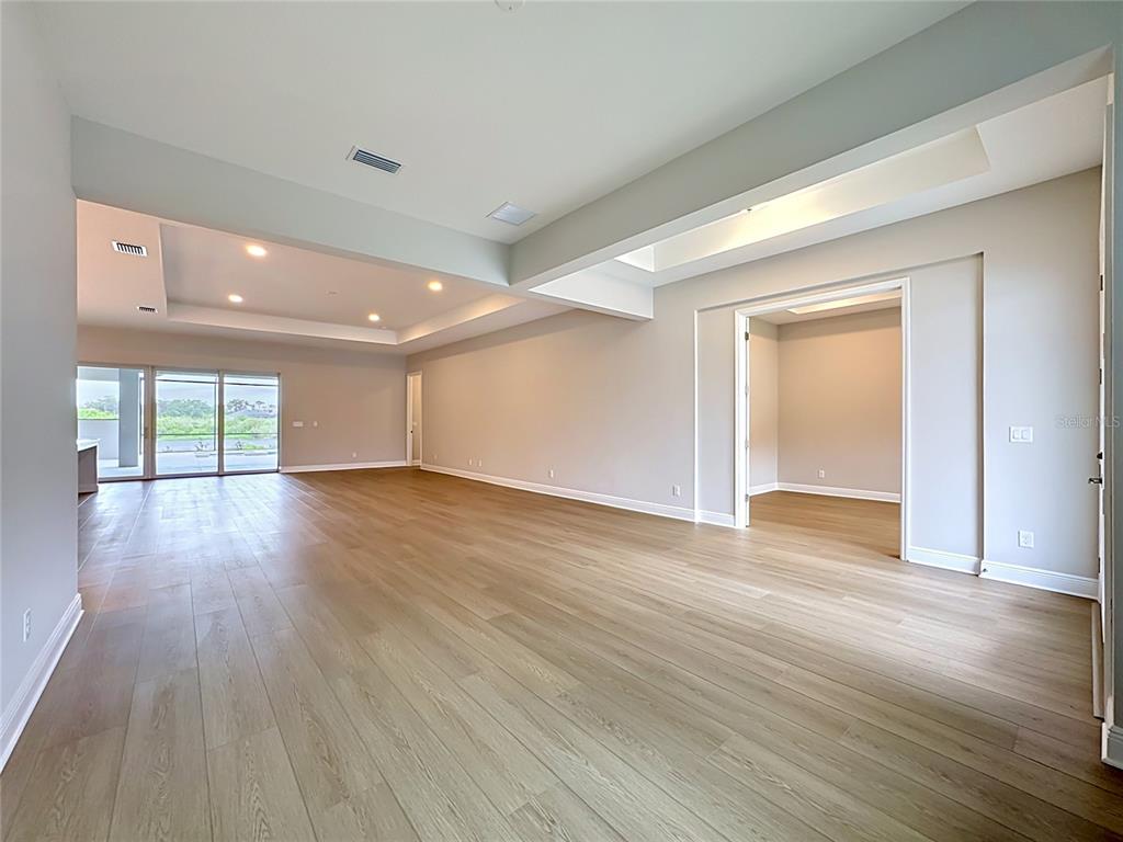 An empty room with light wood flooring, recessed lighting, and a large sliding glass door — 12422 STONEGATE TRAIL, PARRISH, FL